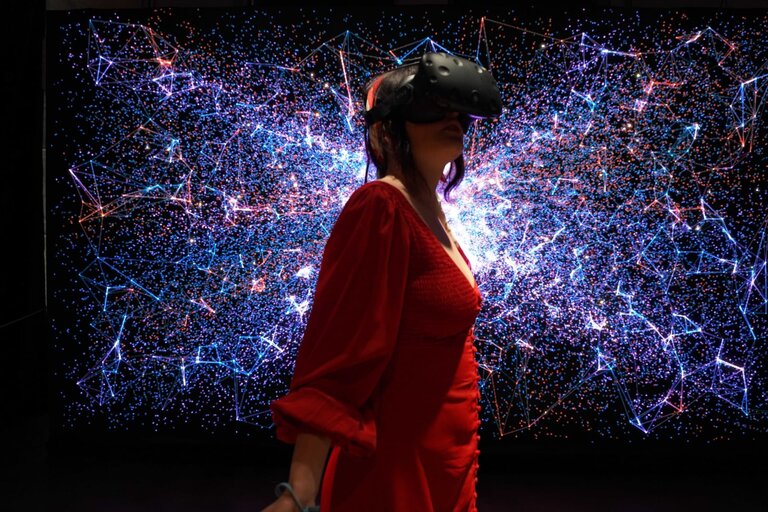 Woman with VR headset, standing in front of a starry sky